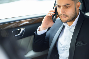 close-up of personable successful man wearing formal wear use smartphone for talking with business partners, solving problems while sitting in car