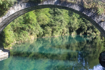 Beautiful view of nature. The bridge over the azure mountain river. Arch over the water. The banks of the river. Stone structure. Camino de Santiago. The way of the pilgrim. Camino Frances.
