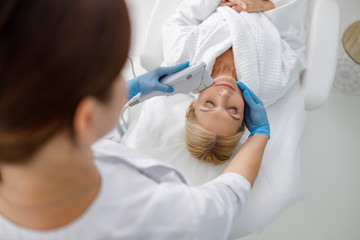 Therapist is doing cosmetic plasma lifting for woman