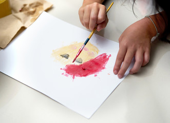 Kid hand make art activity with brush and coloring on paper on floor