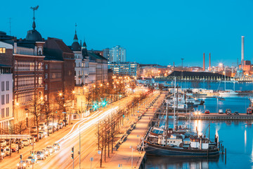 Helsinki, Finland. View Of Pohjoisranta Street And Ships, Boats And Yachts Moored Near Pier In Evening Night Illuminations