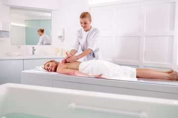 Female masseur doing massage on lady body in spa salon