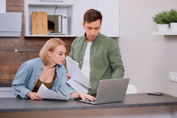 couple check analyzing utilities bills sitting together at kitchen table,at home , handsome husband...