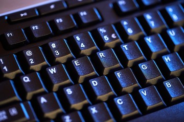 Detail of a black keyboard in blue light