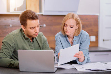 young caucasian husband and wide have active discussion and calculating expences at home together...