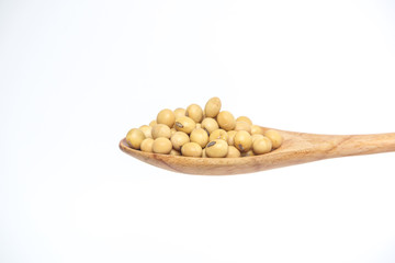 Soybean grain in the wooden spoon isolated on a white background.