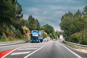 Fototapeta na wymiar Truck Or Traction Unit In Motion On Road, Freeway. Asphalt Motorway Highway Against Background Of Forest Landscape. Business Transportation And Trucking Industry