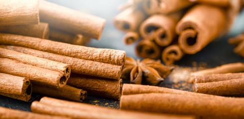 Cinnamon panorama or wide banner concept. Cinnamons stick and powder on dark stone table detail.