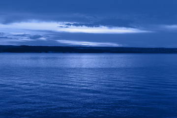 Dark blue night at seaside, dramatic clouds, space for text, selective focus