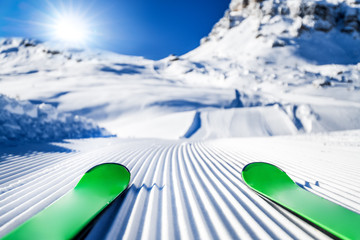 Skis in snow, mountains and ski concept equipments in sunny winter day. Fresh or new groomed slope at best piste resort.