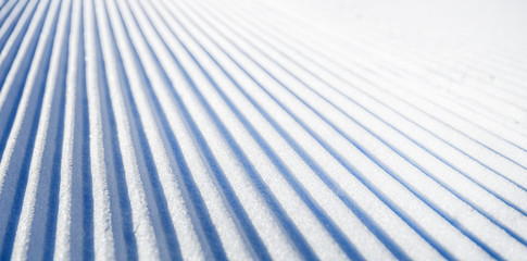 New groomed ski piste or slope. Lines in snow. Winter skiing background, fresh snow on slope. - obrazy, fototapety, plakaty