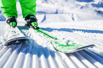 Skis and boots detailed from front view. New groomed piste or slope. Lines in snow with ski.