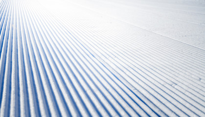 New groomed ski piste or slope. Lines in snow. Winter skiing background, fresh snow on slope.