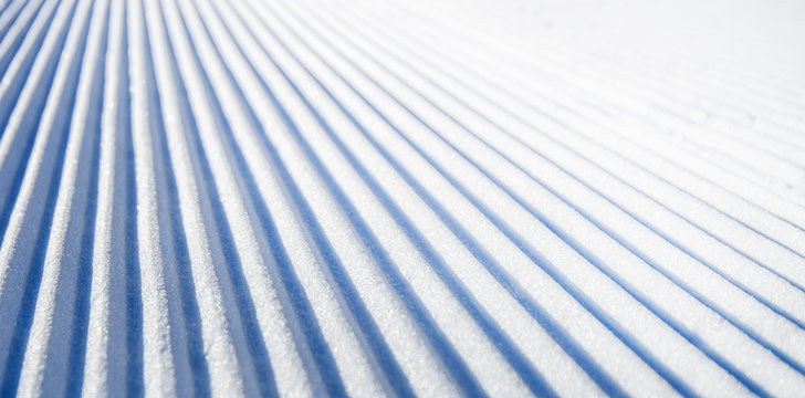 New groomed ski piste or slope. Lines in snow. Winter skiing background, fresh snow on slope.