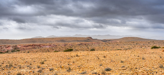 Deserted stony landscape under the dark cloudy sky, multi-shot panorama.