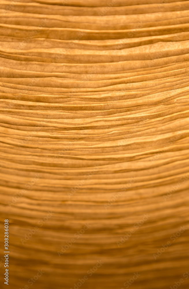 Poster close-up of a creased and backlit yellow paper lampshade. high resolution full frame textured backgr