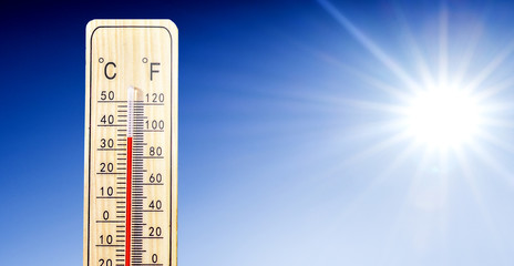 Thermometer in summer day shows or indicate high temperature degree with sun in background..