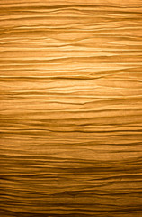 Close-up of a creased and backlit yellow paper lampshade. High resolution full frame textured background.