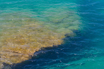 Überspülter Felsen im türkisen Mittelmeer in der Sonne