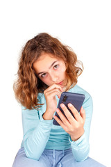 Fototapeta premium Teenager girl with smartphone in her hand looking at the camera thoughtfully