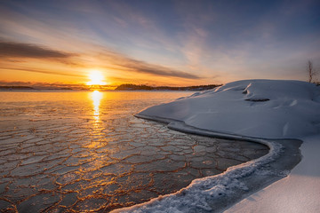 The first ice  off the coast on the water in Lake Ladoga at dawn with fresh snow in winter