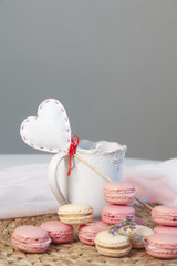 Colored pastel colored macarons with a heart on a cup background lie on a wicker mat. Valentine's day, wedding card concept