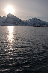 The sunset Through the snowy mountains The sun's rays hit the sea.