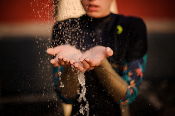 Obraz premium Girl in the black diving suit standing under the shower place hands under water