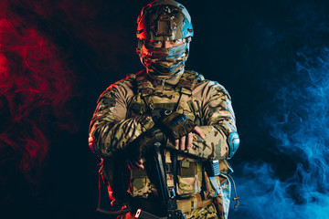 portrait of young military man pointing gun, wearing green army wear, camouflage isolated over...