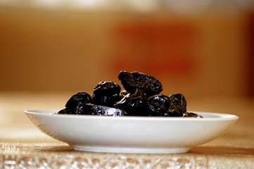 Dessert plums dessert oppressed by smoke in a plate on the table. The background is blurred.