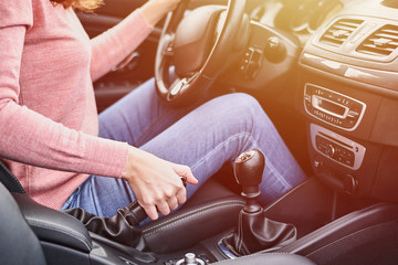 Female hand pulling handbrake in the car. Woman driving the car