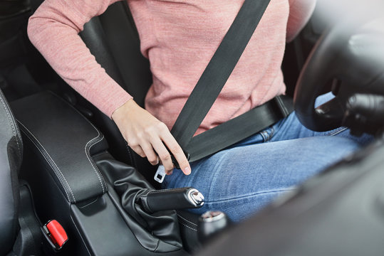 Woman fastening seat belt in the car. Car safety concept