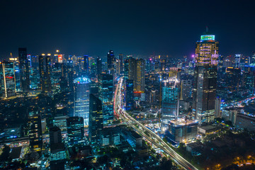 Obraz na płótnie Canvas Aerial view of glowing skyscrapers beside highways