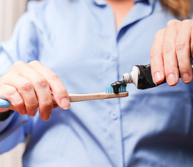 Woman brushing her teeth with activated carbon toothpaste.