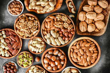 A variety of nuts in wooden bowls from top view. Walnuts, cashew, almond, pistachio, pecan,...