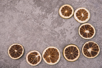 Fototapeta na wymiar Dried oranges and lemons on a grey structured background 