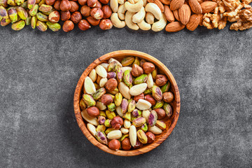 Mix nuts on dark stone table in line top view. Nut background, copy space for text concept.