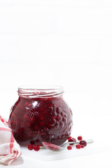 glass jar of cranberry jam on a white table, vertical