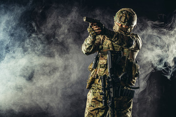 Fototapeta premium brave strong and confident man soldier wearing army clothes, green camouflage stand holding gun, ready to shoot