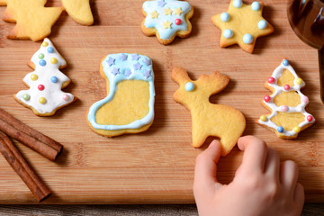 Top view of children fingers touch Christmas cookies and biscuits festive background arranged on a rustic wooden table with spicy speculoos, confections, copy space