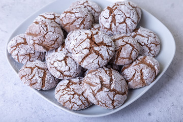 Chocolate cookies with cracks, strewed with icing sugar. Homemade baking. Selective focus, close up.