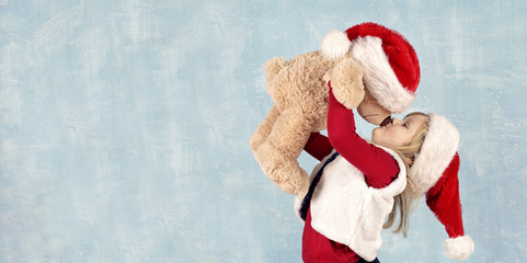 fröhliches Mädchen küsst Teddybär - Weihnachten