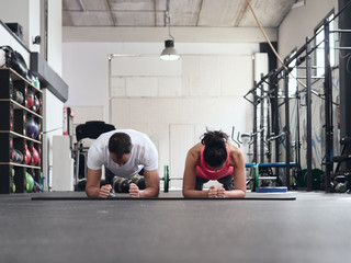 Young couple doing planks at an empty crossfit gym