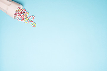 Cup full of Christmas candy cane on a blue background.