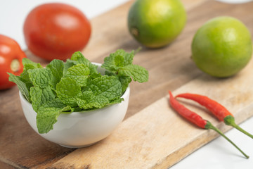 peppermint in small cup on board and  Vegetable with white background