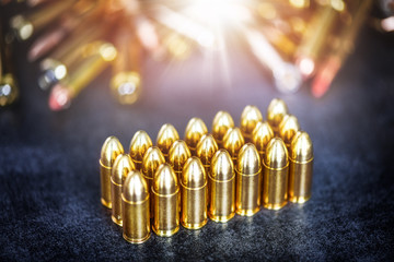 9mm rounds or bullets ammonution on dark stone table. Bullet pile in color background. Magazines,...