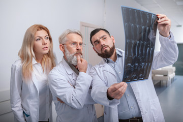 Team of doctors examining MRI scan together. Medical workers looking at MRI scan at the hospital