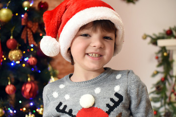 Portrait 0f a happy little boy with Santa hat. Child with Santa hat under a Christmas tree