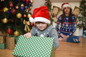 Mom and son opening Christmas gift. Mother watch son opening present for a New Year