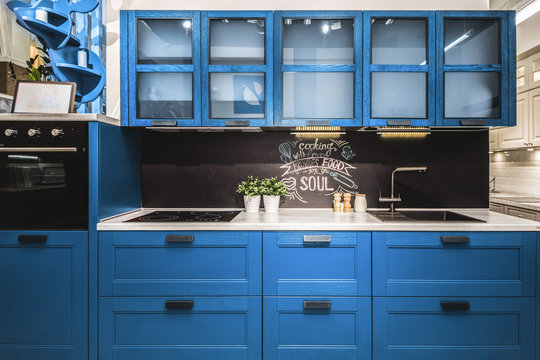 Modern red kitchen interior with black brick walls, wooden countertops with a built in sink and a cooker. classic blue, pantone color of the year 2020